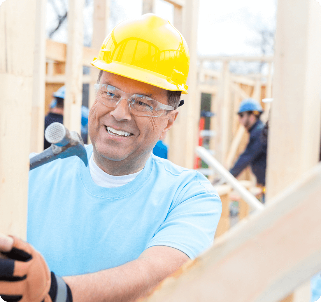 Smiling construction worker hammering wooden frame.